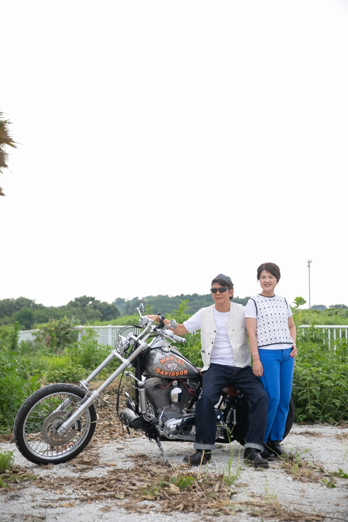 空の下、草原でバイクと並ぶふたり