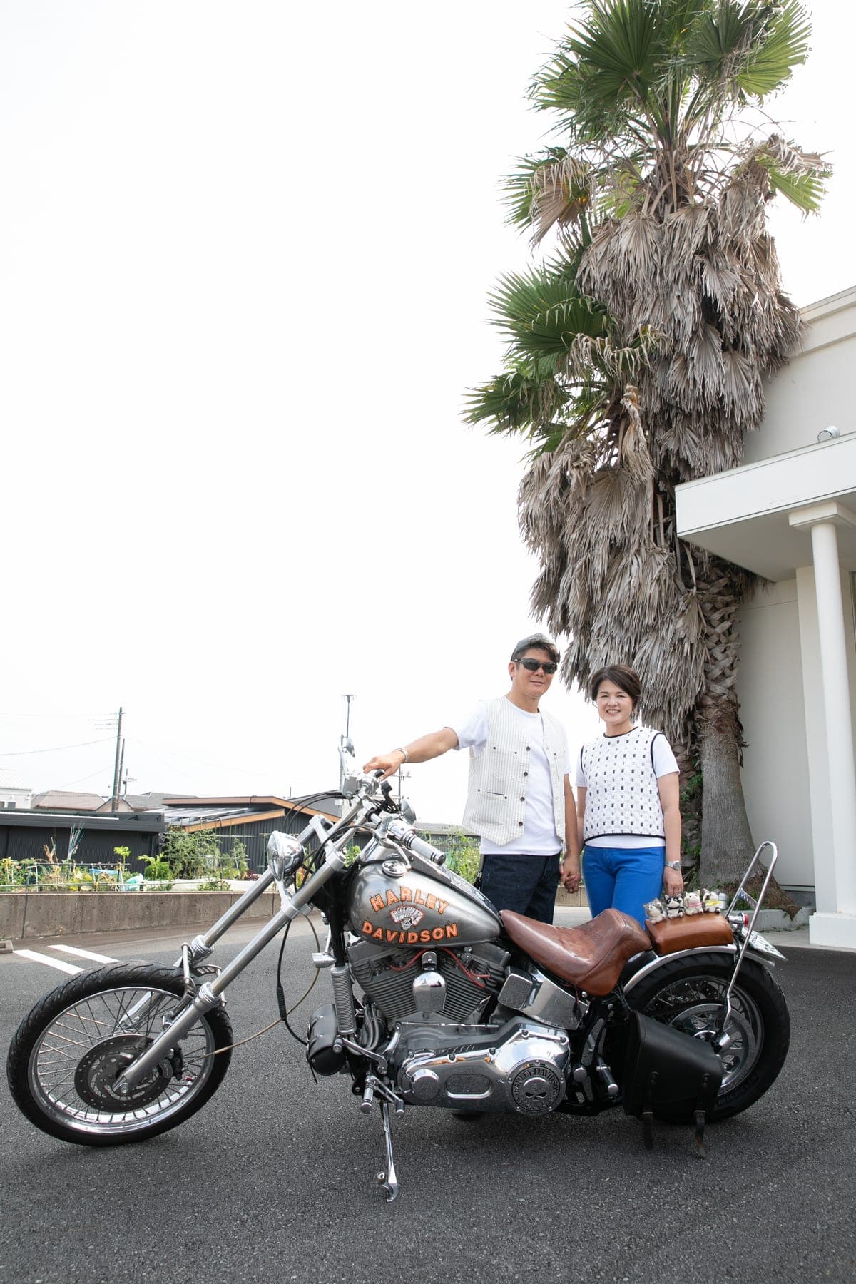 ヤシの木の前でバイクの横に立つふたり