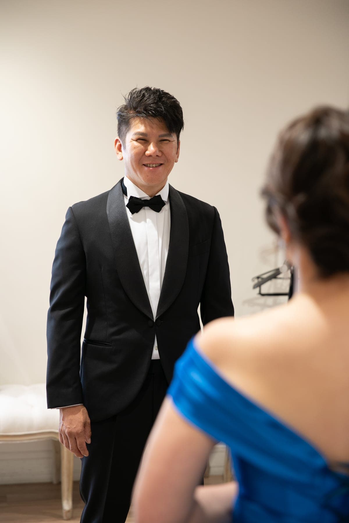 ドレスに着替えた妻を見て笑うタキシードの男性